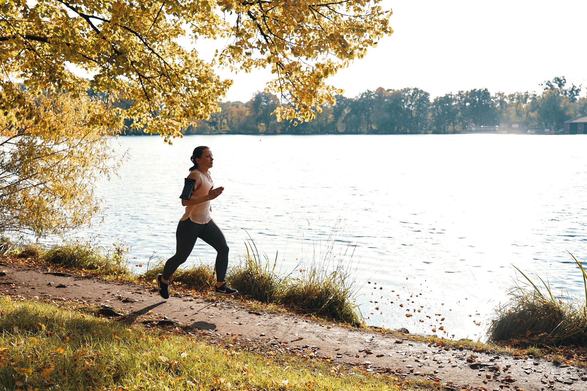Woman wearing Fidlock Phone Arm Band while running by river