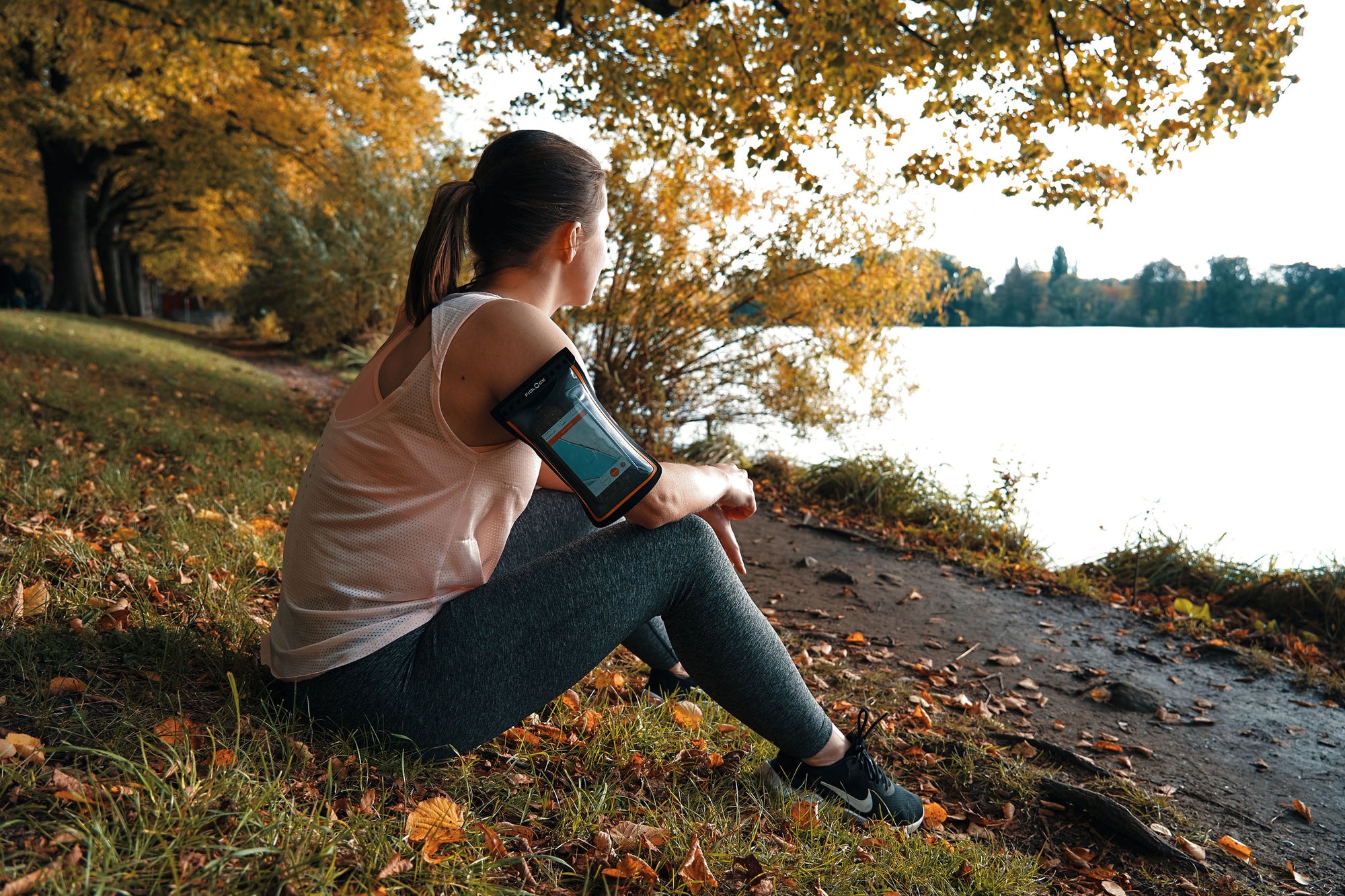 Woman wearing Fidlock Phone Arm Band while sitting by river