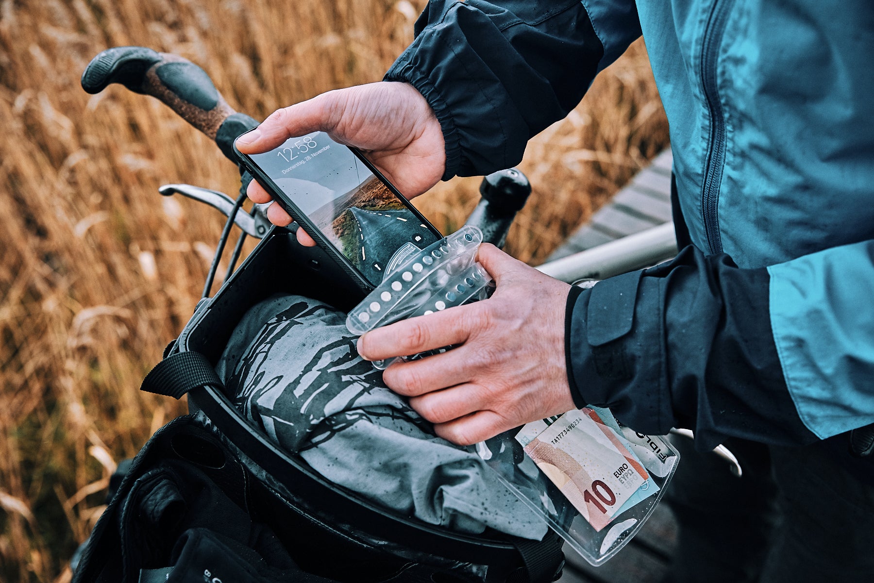 Man on bike putting cell phone into Fidlock Hermetic dry bag